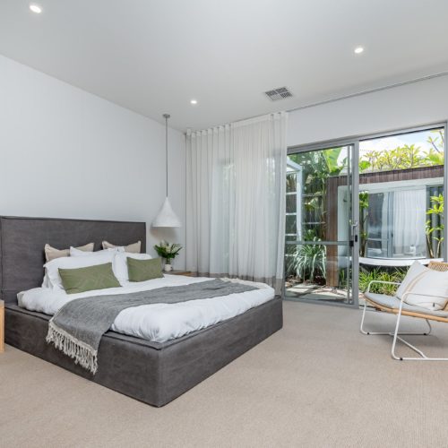 Large modern bedroom with high ceilings and oak wood furnishings.