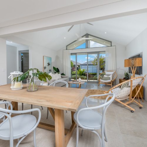Dining and living area of home with high ceilings and neutral tones.