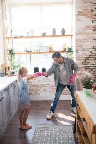 Father and daughter having fun with cleaning gloves on and ready to clean.