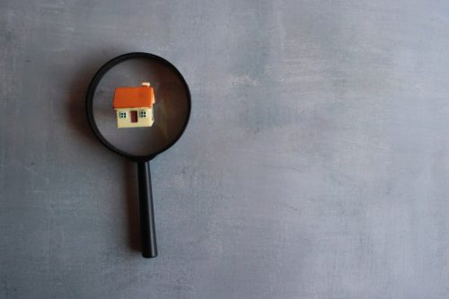 A magnifying glass and miniature house depicted the differenc between a property valuation and appraisal.