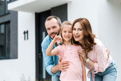 Family standing out the front of a home they just purchased.