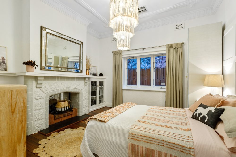 Main bedroom with old fire place and large cascading light fitting.