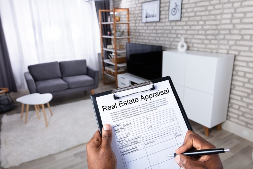 Over the shoulder view of real estate agent conducting a property valuation, wirting notes on a clipboard.