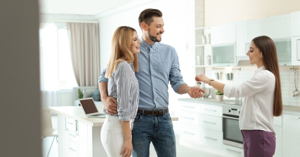 Landlord handing keys to a couple renting a property.