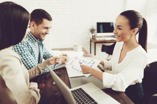 A happy couple talking to a smiling property manager.